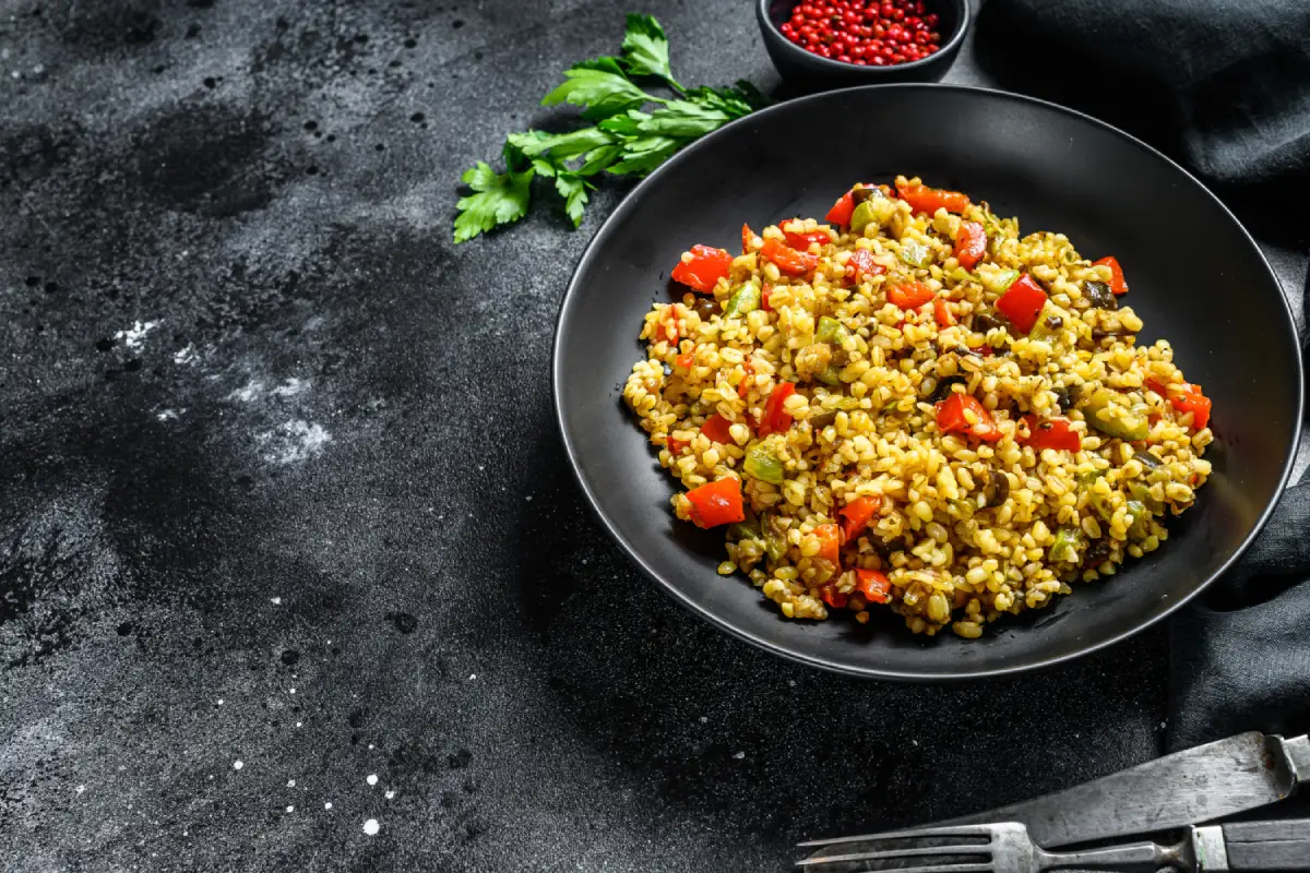 A skillet full of bulgur and mixed vegetables, showcasing a healthy and colorful meal.
