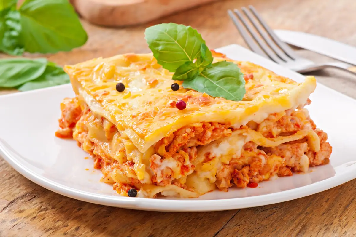 A luscious slice of lasagna layered with cheese and tomato sauce, adorned with fresh basil.