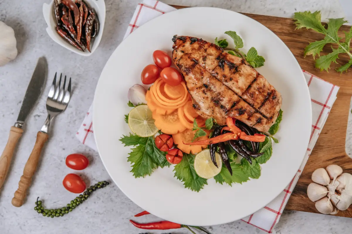 Grilled chicken breast on a bed of mixed greens with tomatoes, carrots, red peppers, cucumber, and fresh mint.