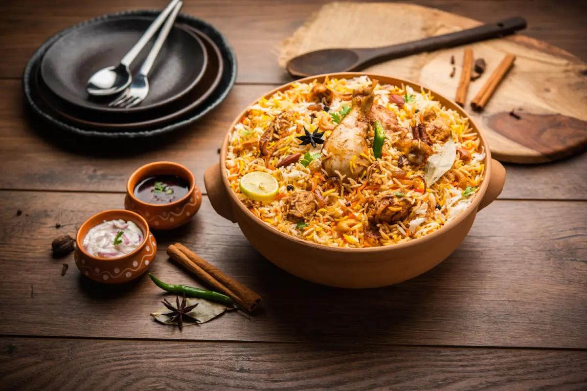 An inviting bowl of traditional chicken biryani richly flavored with spices and garnished with lemon and herbs.