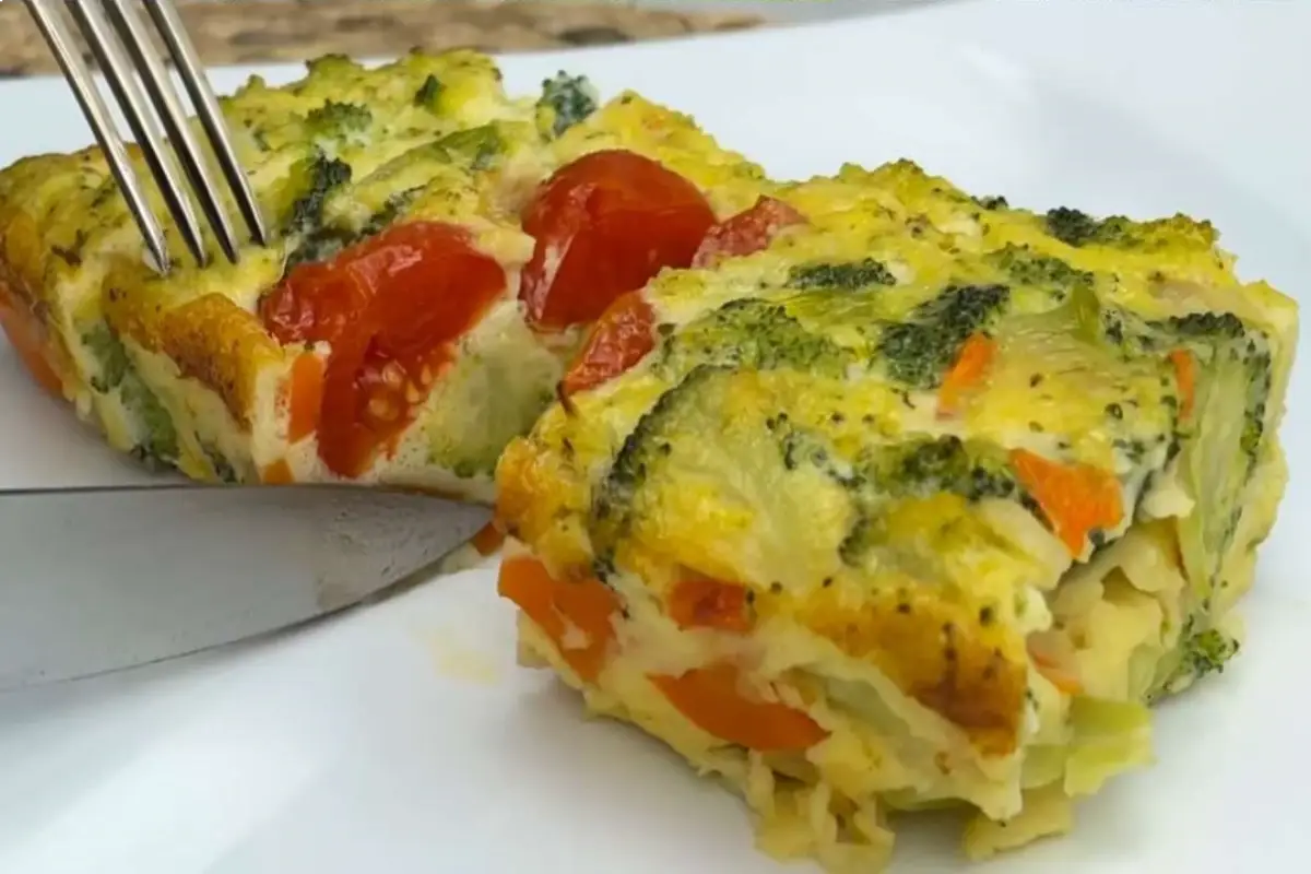 A slice of Healthy Broccoli Egg Bake on a plate with a fork, showcasing the cherry tomato topping.