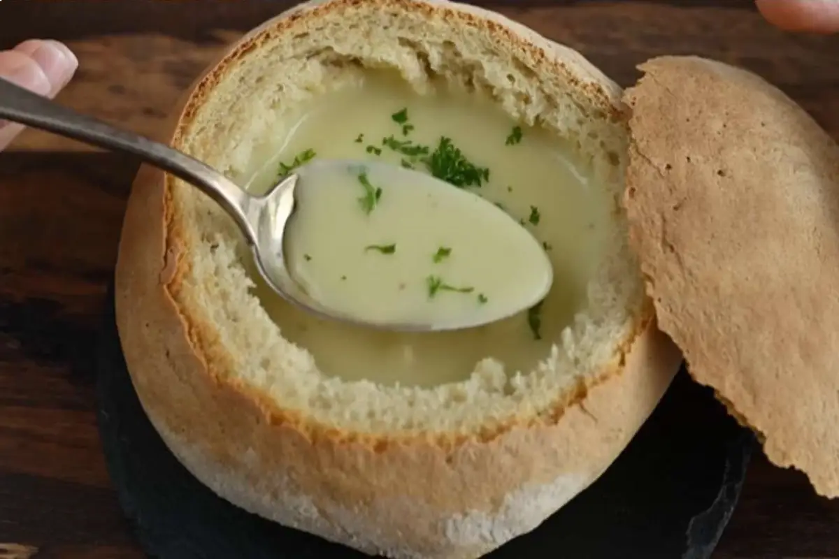 Spoon scooping up Austrian Garlic Soup from a bread bowl.